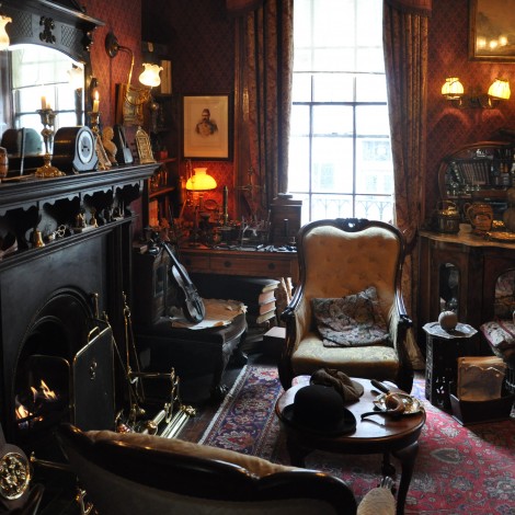 What appears to be a historic room of an old home. Outfitted with original furniture from 1800's appears to be a den with large chairs, fireplace, wall sconces